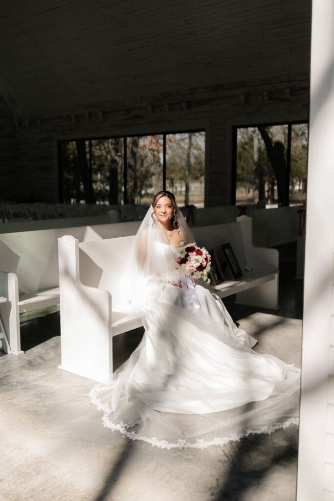 Bride posing on the pews at Soli Deo Gloria Weddings and Events in Decatur, TX