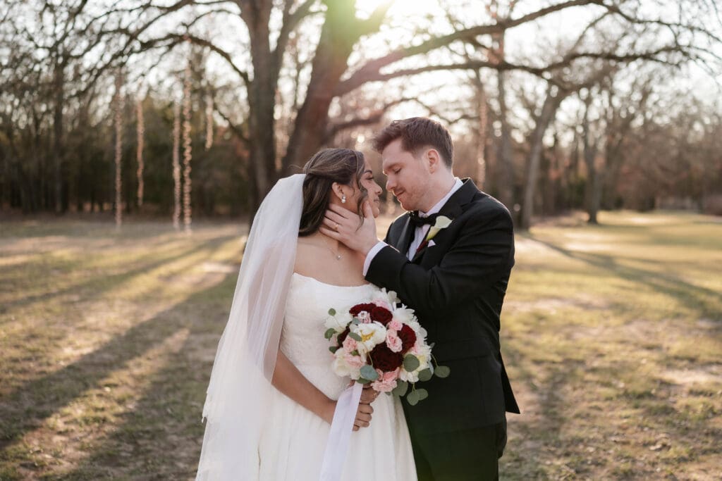 Bride and groom embrace in front of a large tree at Soli Deo Gloria Weddings and Events in Decatur, TX