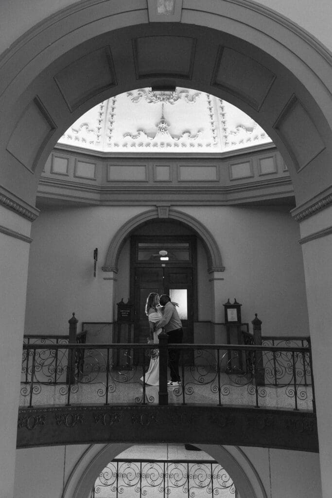 Couple captured kissing and interacting during their intimate Fort Worth courthouse wedding indoors.