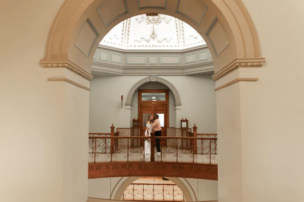 Couple captured kissing and interacting during their intimate Fort Worth courthouse wedding indoors.