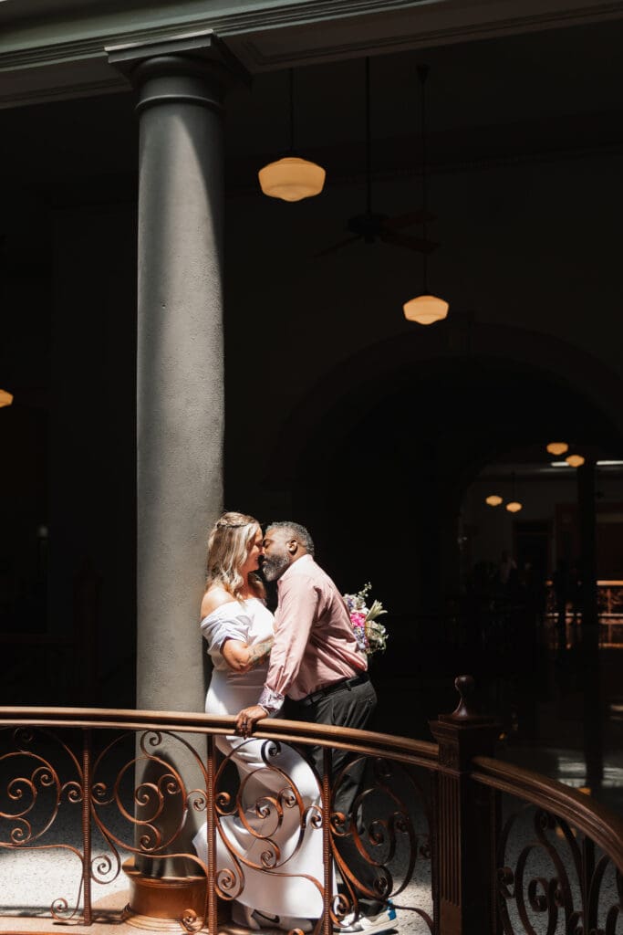 Moody, creative portrait of a couple kissing inside the Tarrant County Courthouse during their elopement.