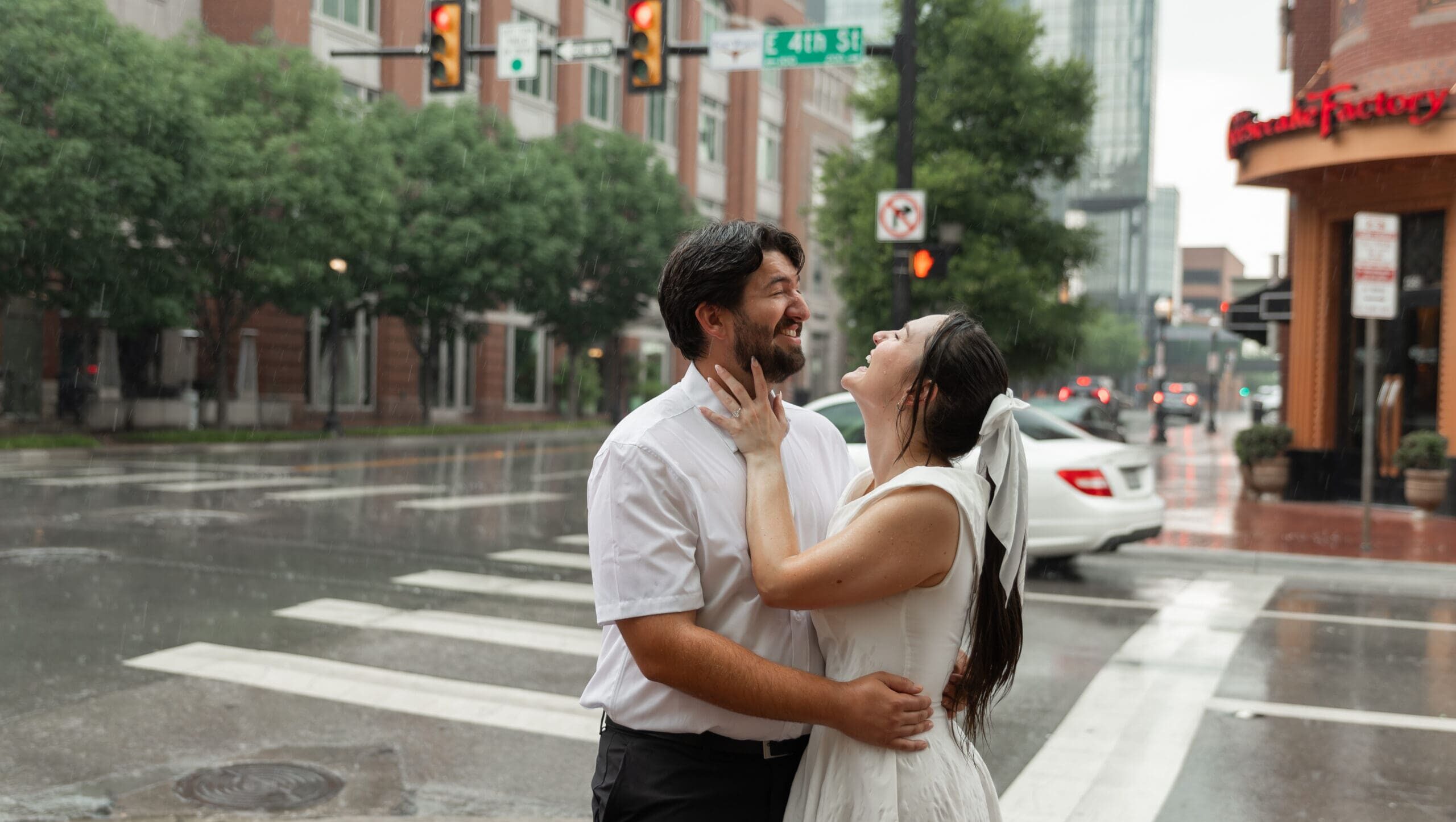 Engaged couple laughing and embracing in the rain during their downtown Fort Worth engagement photoshoot