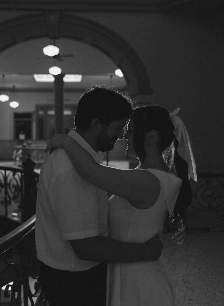 Black-and-white image of the couple sharing an intimate embrace inside the Tarrant County Courthouse.