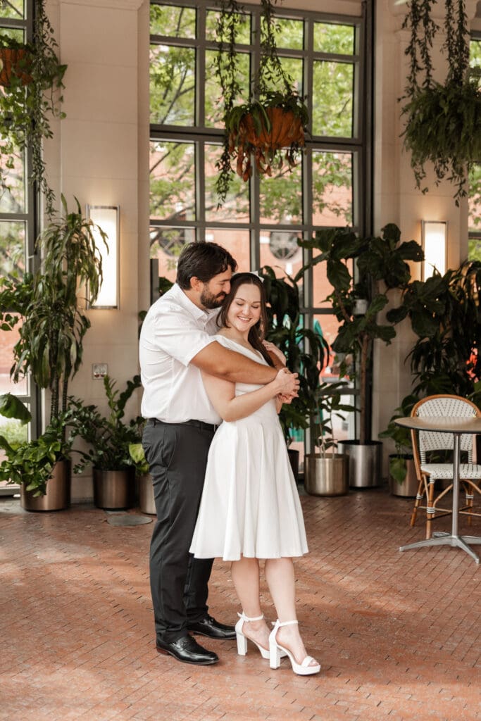 Couple embracing in the Sundance Square Pavilion greenhouse during their downtown Fort Worth engagement session
