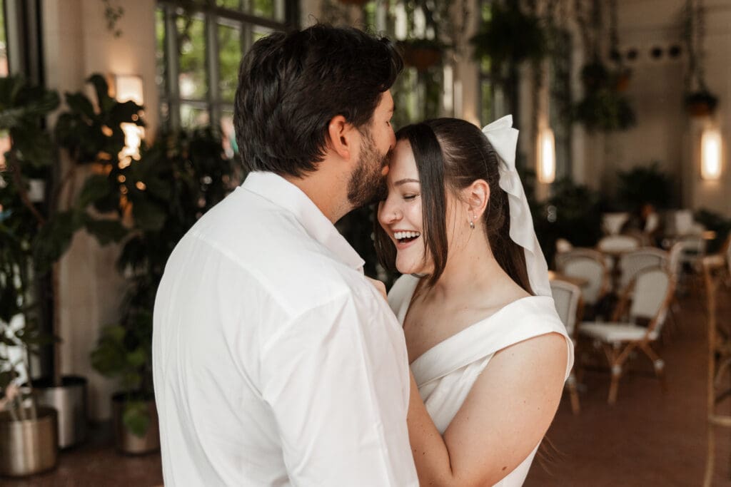 Couple kissing in the Sundance Square Pavilion greenhouse during their downtown Fort Worth engagement session

