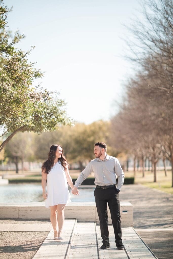 Engaged couple at Kimbell Art Museum, Fort Worth, holding hands and walking across steps