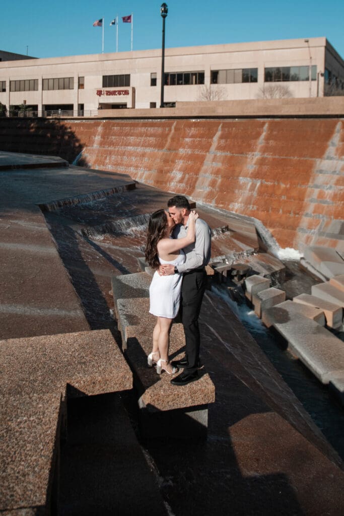 Engaged couple at the Water Gardens, Fort Worth, kissing golden-hour engagement photos
