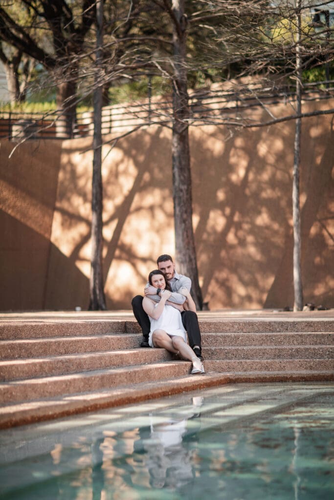 Engaged couple at the Water Gardens, Fort Worth, embracing each other during golden-hour engagement photos