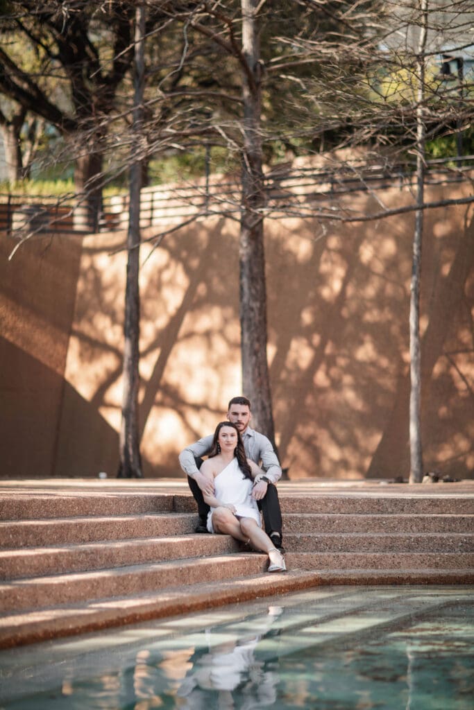 Engaged couple at the Water Gardens, Fort Worth, embracing each other during golden-hour engagement photos