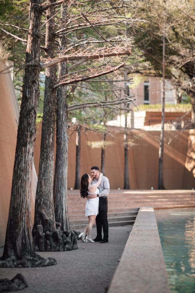 Engaged couple at the Water Gardens, Fort Worth, embracing each other during golden-hour engagement photos