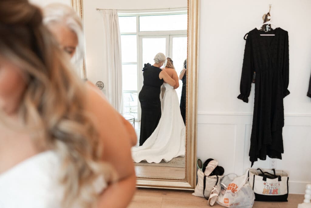 Bride and mother putting on wedding dress at The Gardenia Venue in Valley View, TX