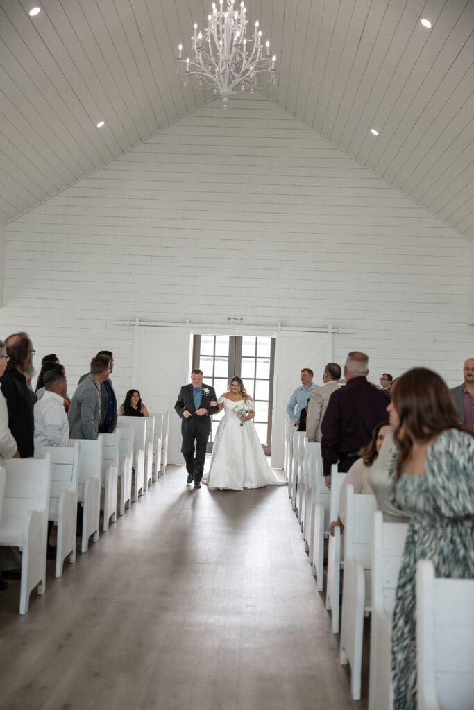 Father walking bride down the aisle in the chapel at The Gardenia Venue in Valley View, TX