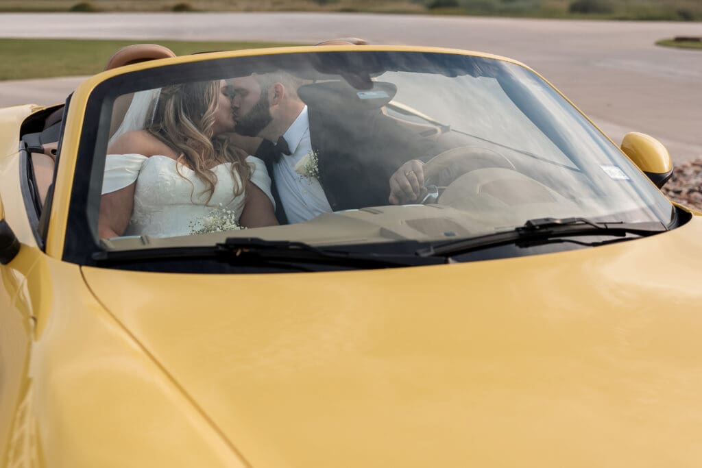 Bride and groom kissing in the Porsche sports car at The Gardenia Venue in Valley View, TX