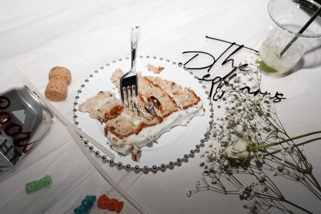 Detail shot of the wedding cake, drinks, couple's rings, and flowers at  The Gardenia Venue in Valley View, TX