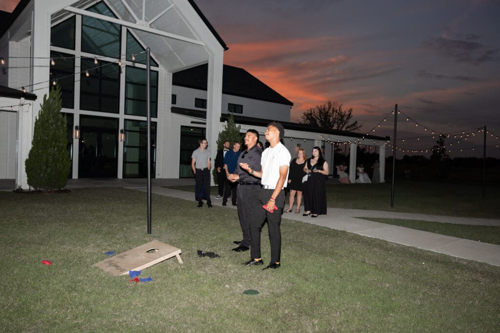 Wedding guests playing cornhole at The Gardenia Venue in Valley View, TX