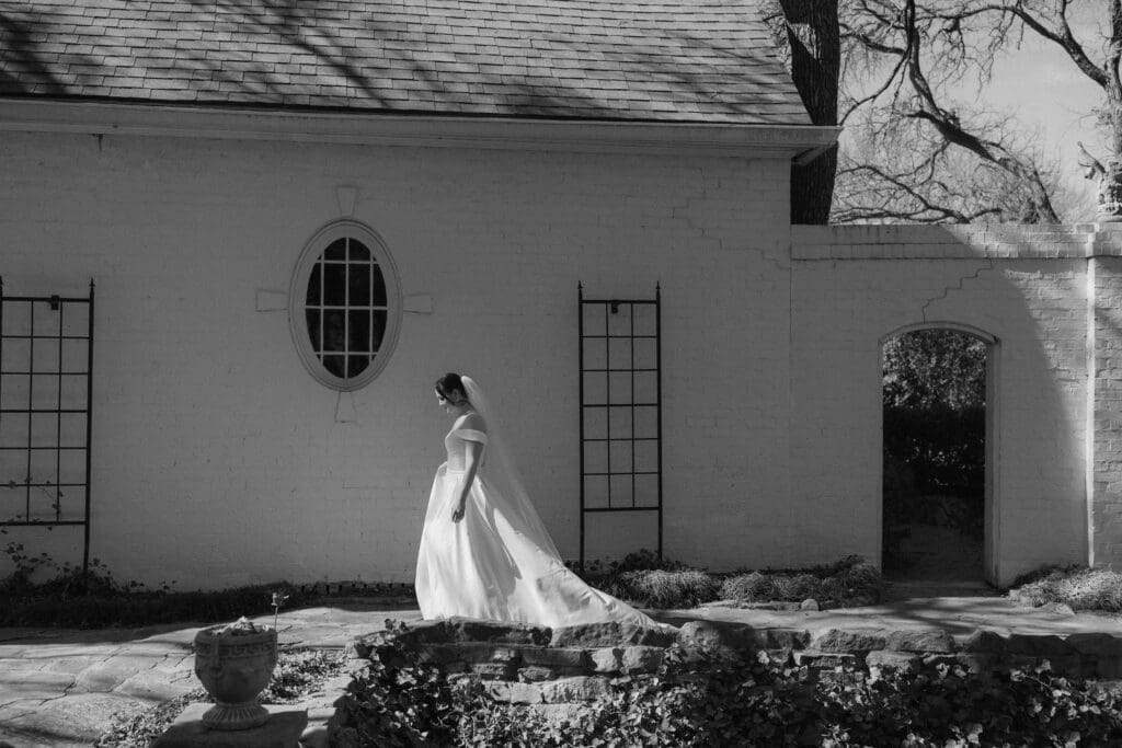 Moody, cinematic bridal portrait of a bride walking along the paths of Chandor Gardens in Weatherford, TX