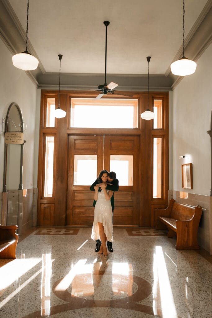 Woman and man cuddling on in the Fort Worth courthouse during their Fort Worth engagement session