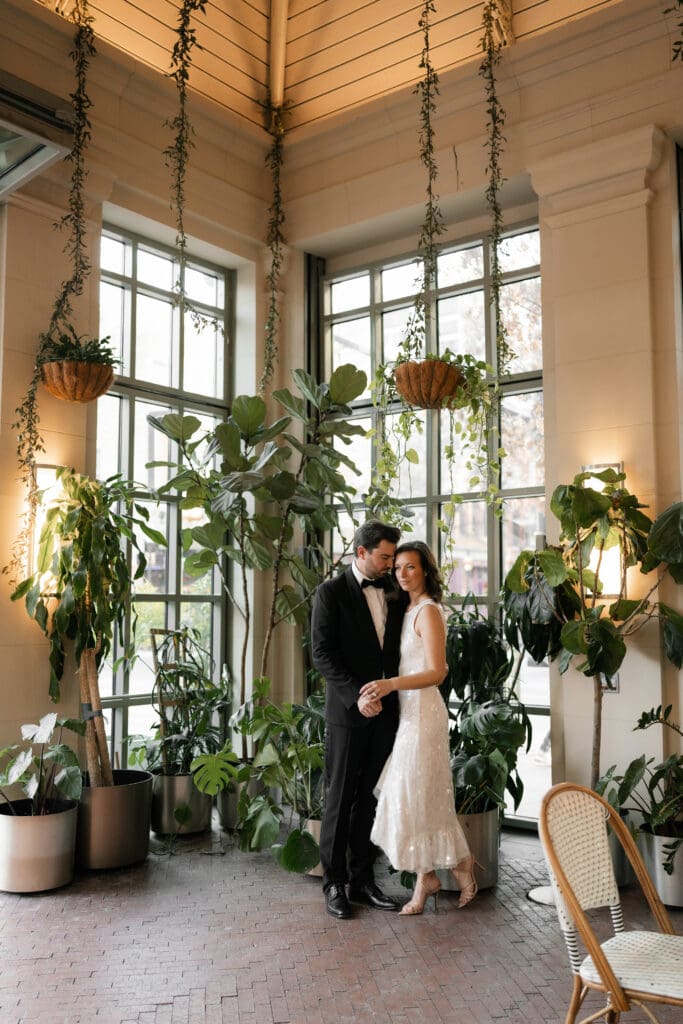 Woman and man cuddling inside the Sundance Square Pavilion greenhouse during their engagement session