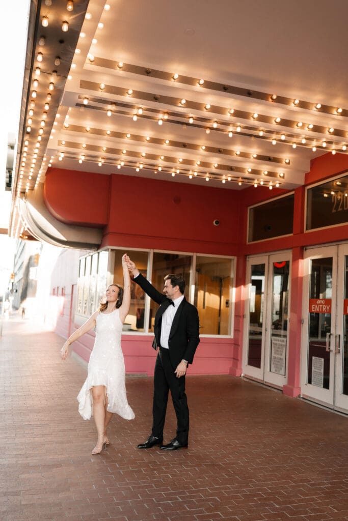 Woman and man dancing under the cinema lights in downtown Fort Worth during their photo session