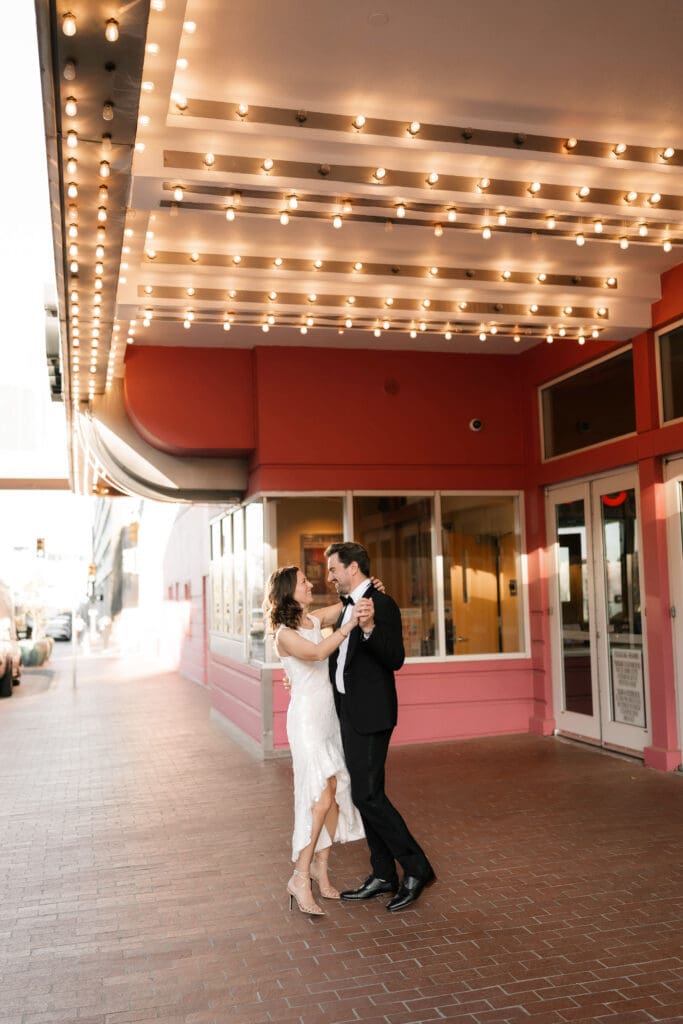 Woman and man dancing under the cinema lights in downtown Fort Worth during their photo session