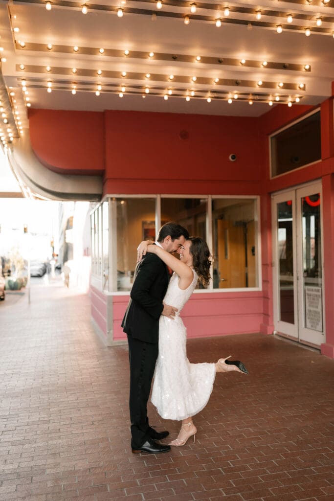Woman and man dancing under the cinema lights in downtown Fort Worth during their photo session