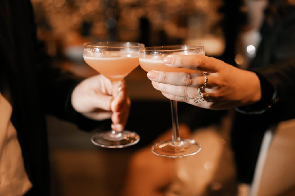 Direct flash photo of man and woman holding their drinks and cheers 