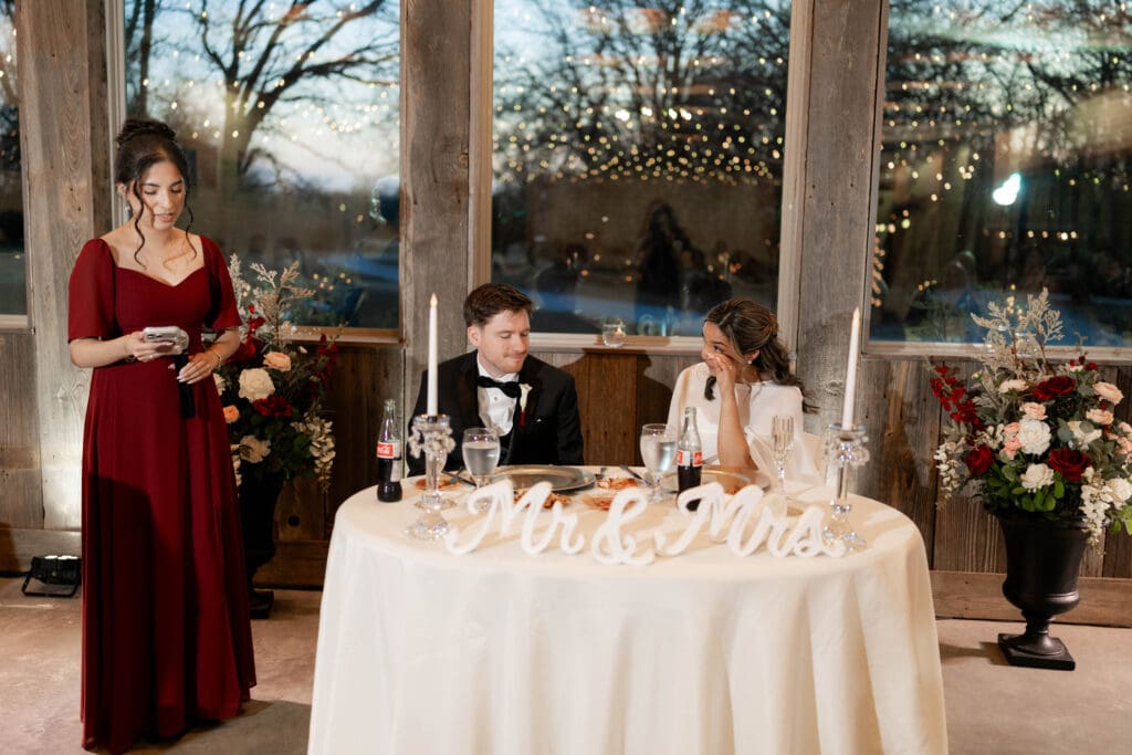 Bride tearing up while her bridesmaid gives a speech