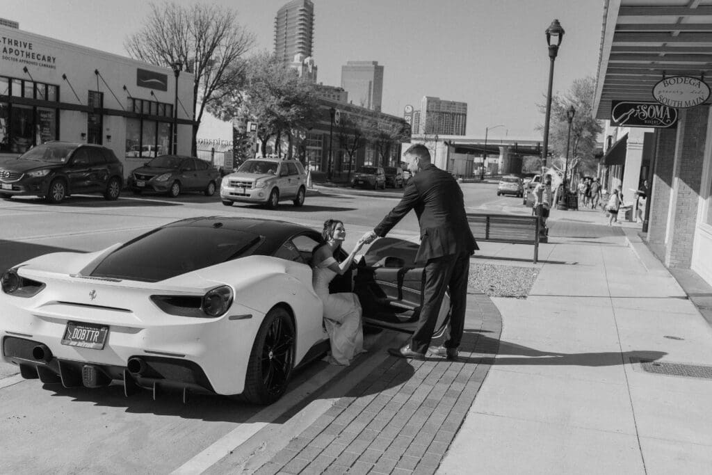 Groom helping bride out of his Lamborghini 