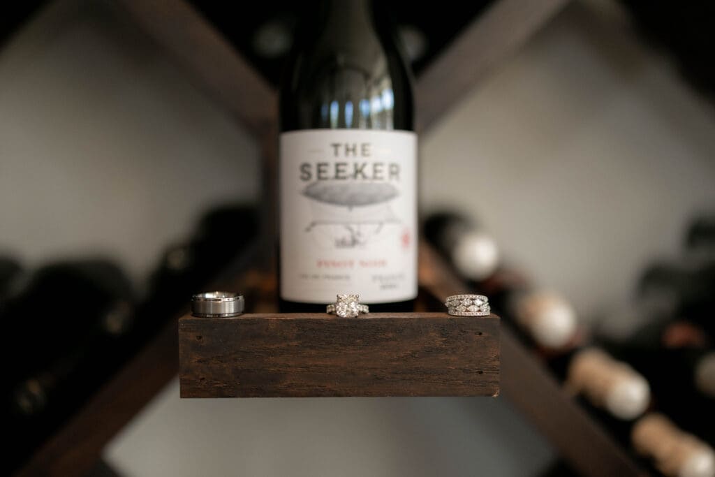 Close up shot of bride and groom's wedding rings on wine bottle rack