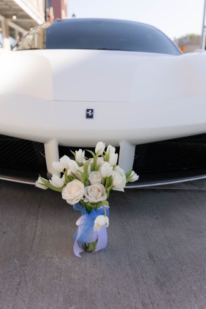 Detail shot of bride's flower bouquet in front of groom's Lamborghini