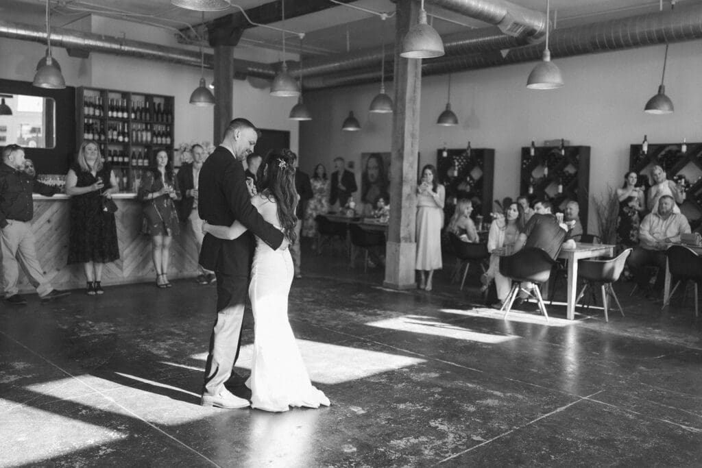 Bride and groom's first dance with guests watching at Soma Winery in Fort Worth, TX