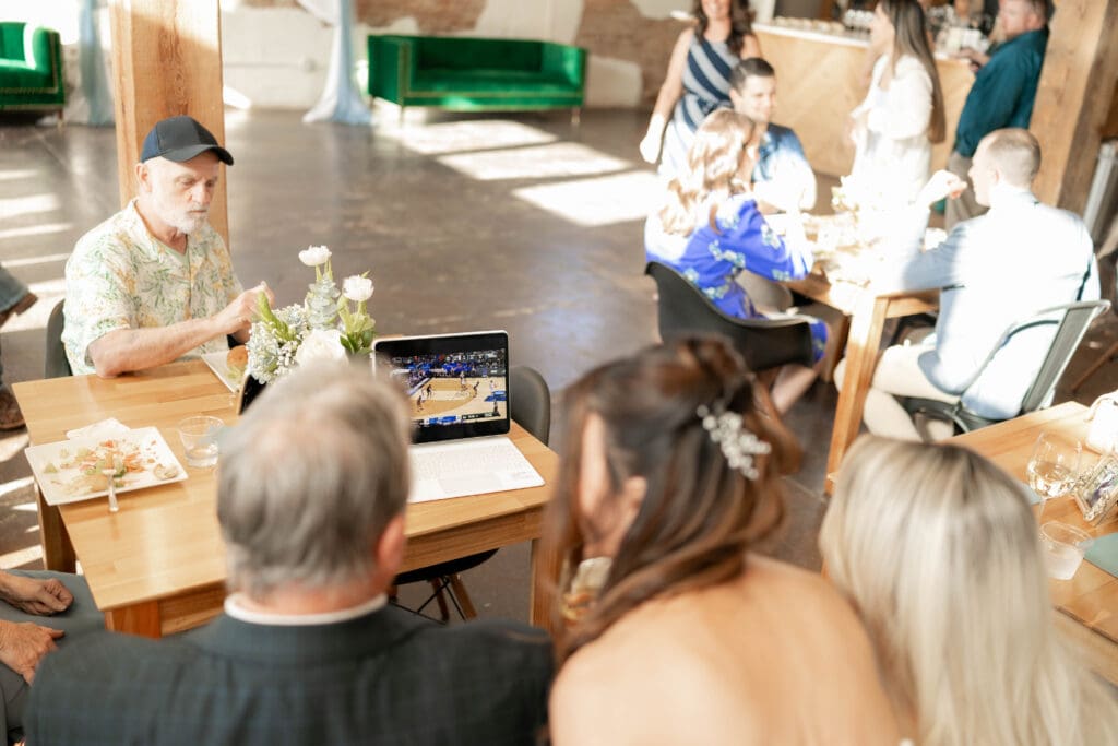 Bride watching the basketball game with her father and sister during her wedding reception