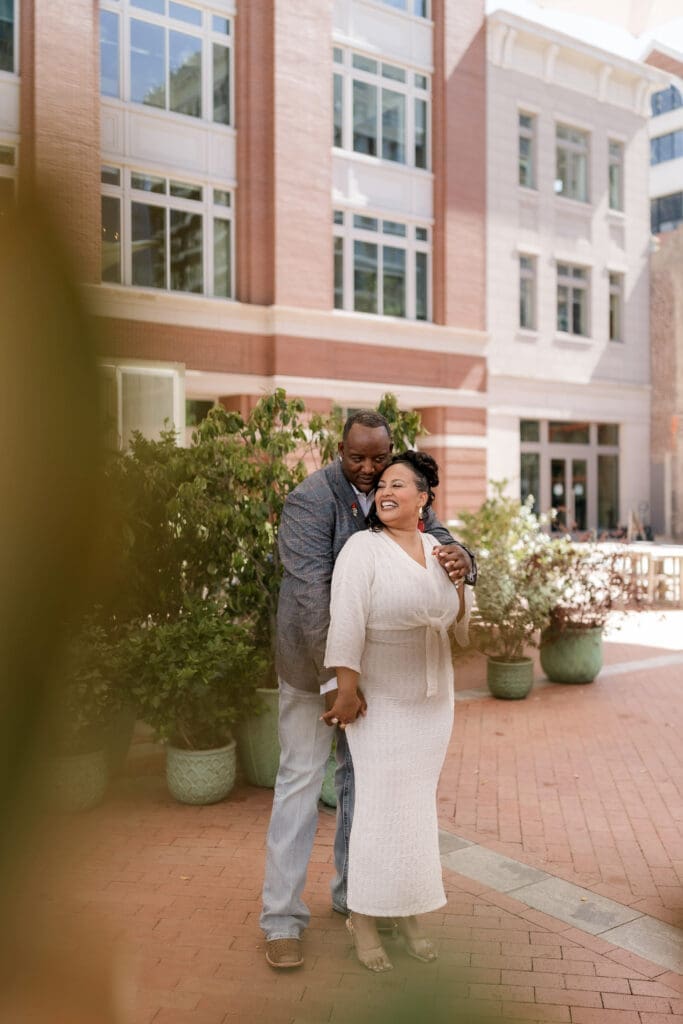 Man and woman posing during their engagement session at Sundance Square in Fort Worth, TX