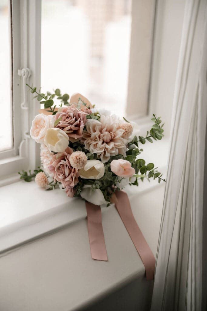 Bride's bouquet sitting on window sill in soft, diffused lighting