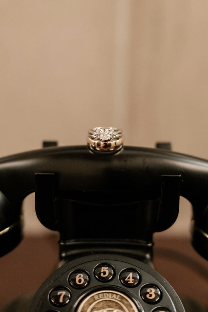Close up of bride and groom's rings atop a vintage telephone