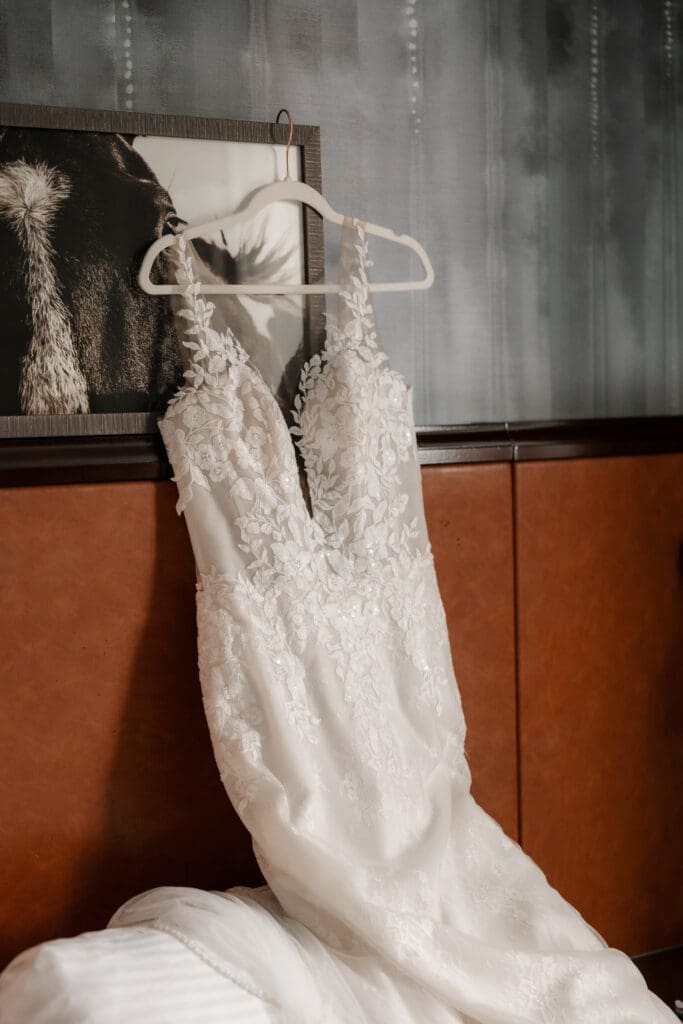 Bride's wedding dress hanging above the bed in the hotel suite
