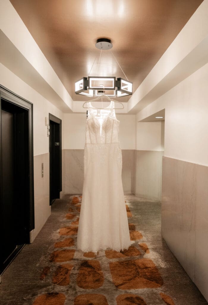 Wedding dress hanging from chandelier in hotel lobby