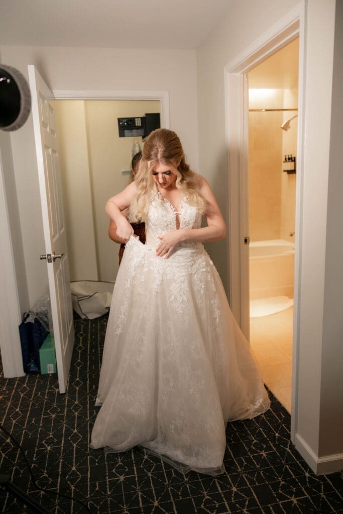 Bride putting on her wedding dress after finishing getting ready