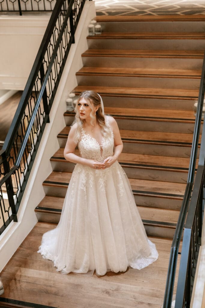 Bride along the grand staircase in hotel, posing under soft lighting
