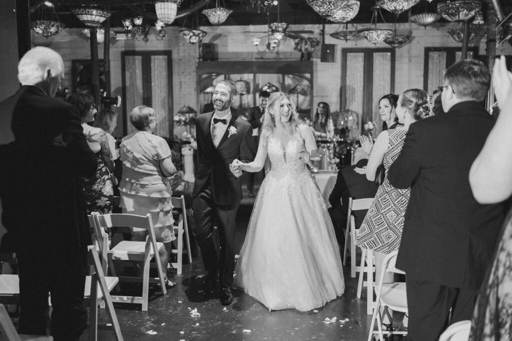 Katrina and Nick walking down the aisle as husband and wife at their Nouveau Antique Bar wedding in Houston, TX