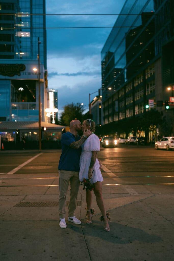 Photo of bride and groom kissing in front of the Arrogant Butcher in downtown Phoenix at blue hour