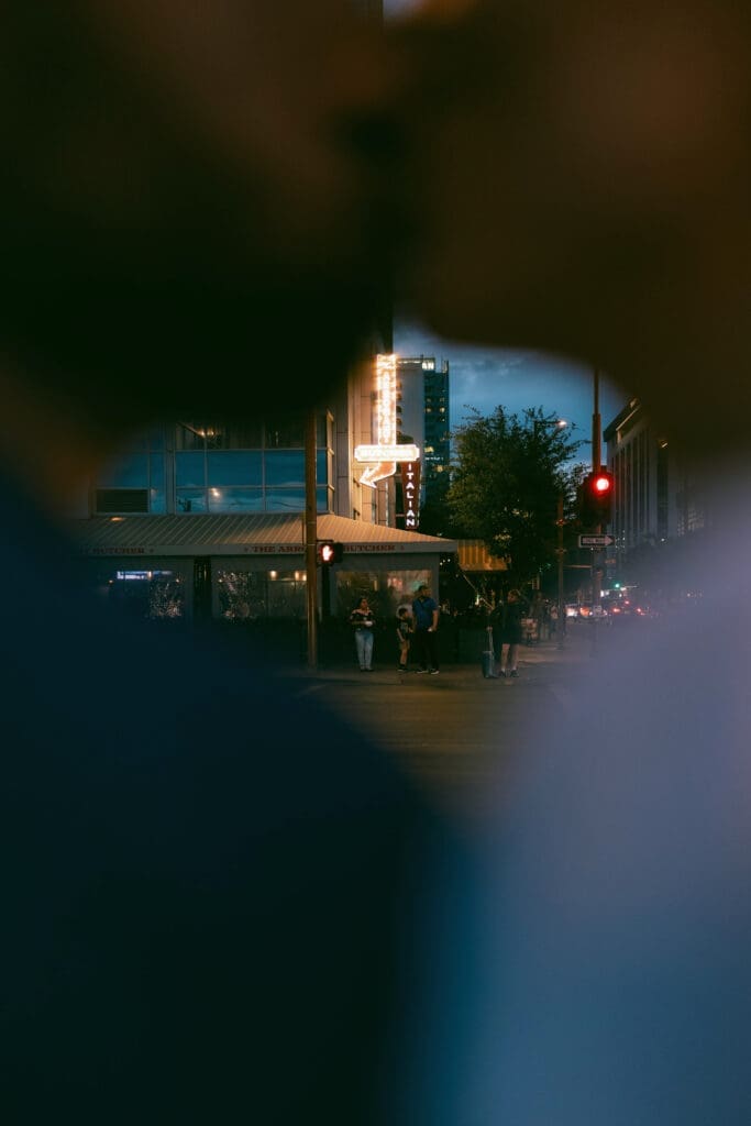 Photo of bride and groom kissing in front of the Arrogant Butcher in downtown Phoenix at blue hour