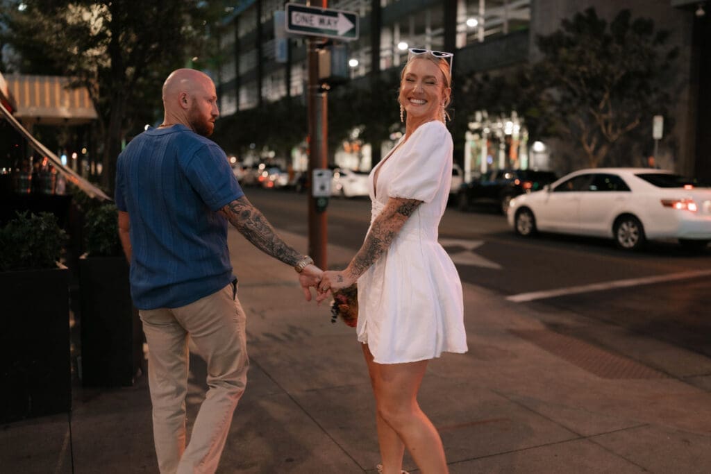 Photo of bride and groom walking across the street in downtown Phoenix at blue hour