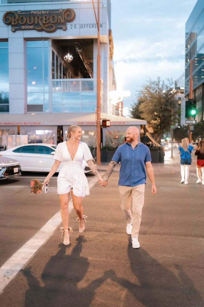 Photo of bride and groom walking across the street in downtown Phoenix at blue hour