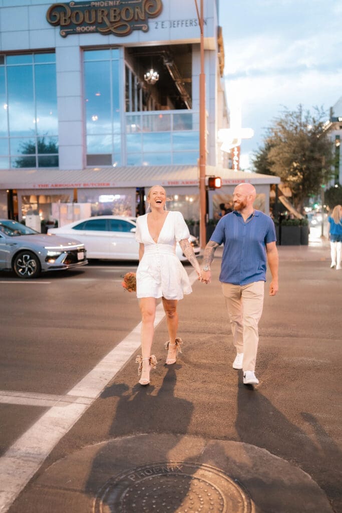 Photo of bride and groom walking across the street in downtown Phoenix at blue hour