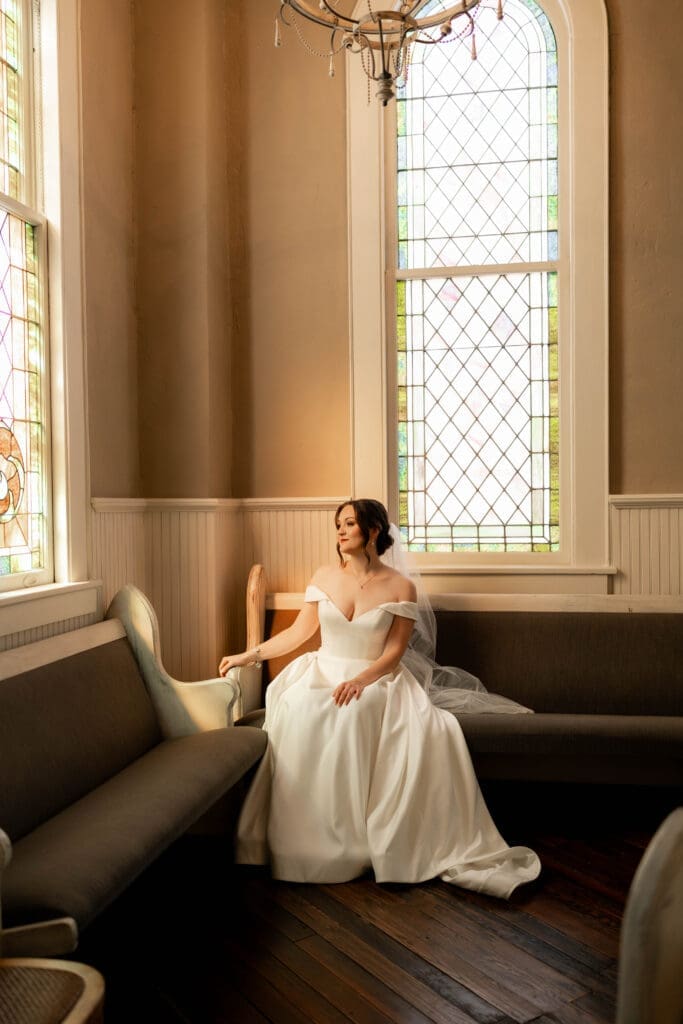 The 1906 wedding photographer taking photos of bride and groom in chapel against the stained glass windows