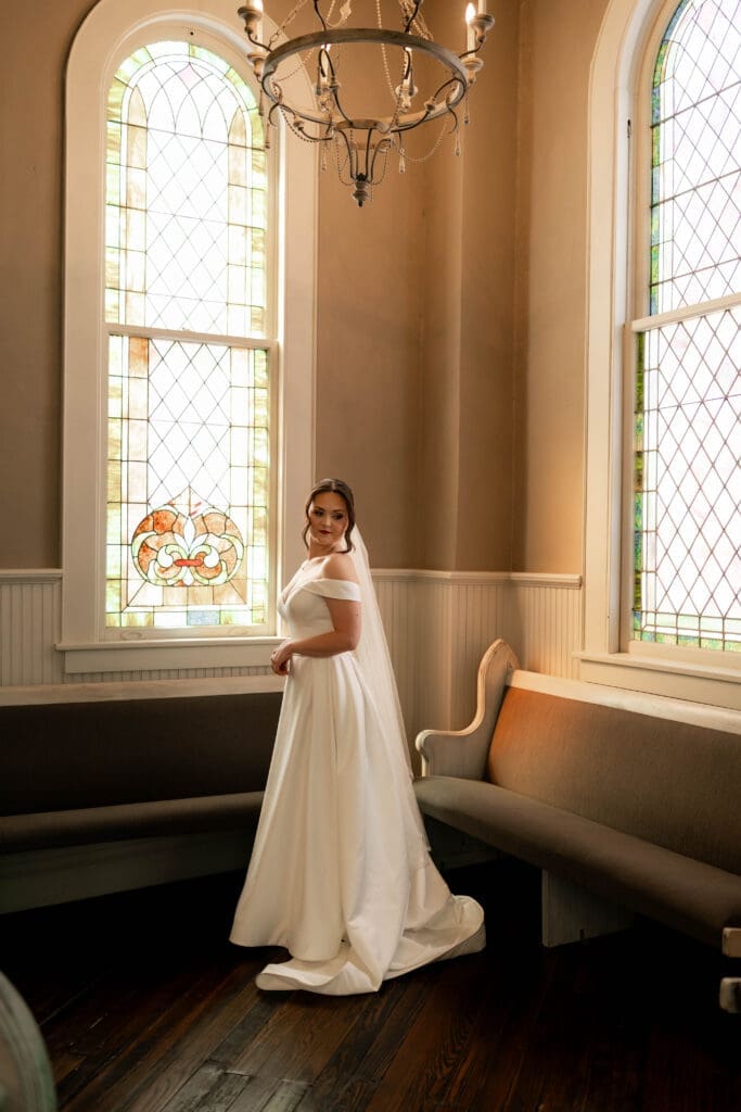 The 1906 wedding photographer taking photos of bride and groom in chapel against the stained glass windows