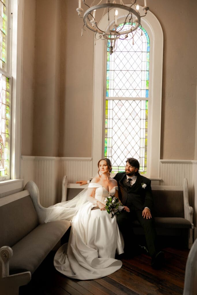 The 1906 wedding photographer taking photos of bride and groom in chapel against the stained glass windows