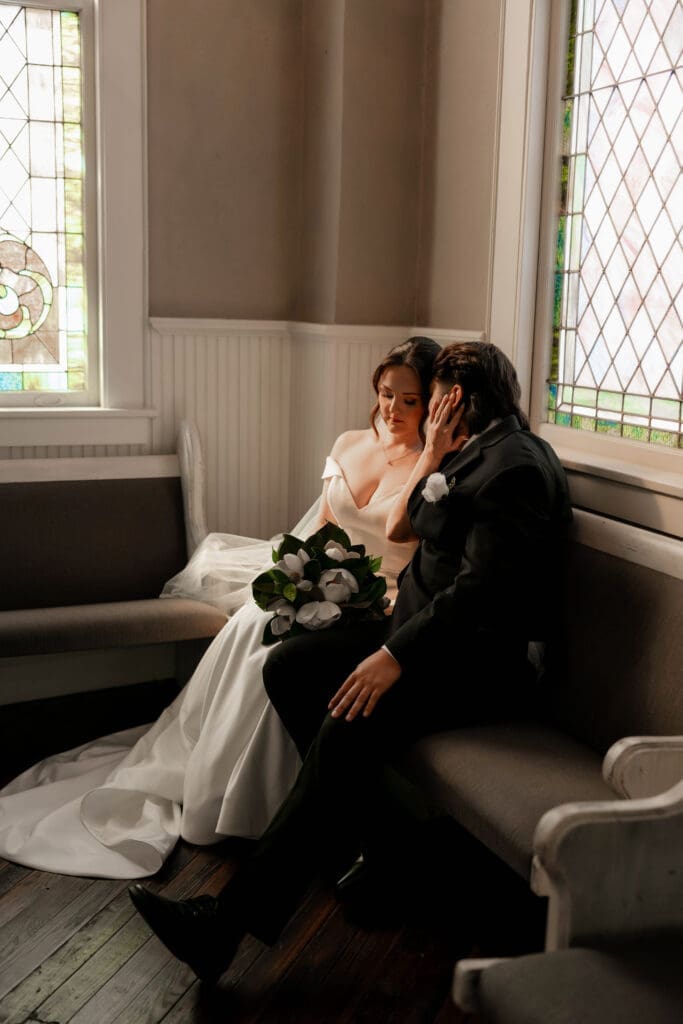 The 1906 wedding photographer taking photos of bride and groom in chapel against the stained glass windows