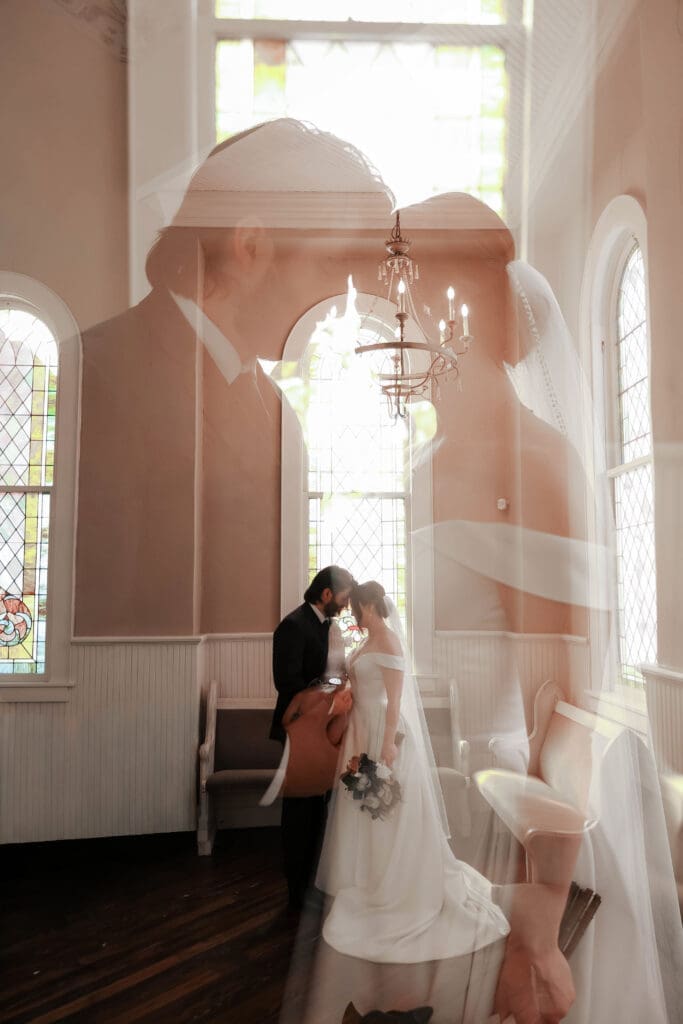 The 1906 wedding photographer taking photos of bride and groom in chapel against the stained glass windows